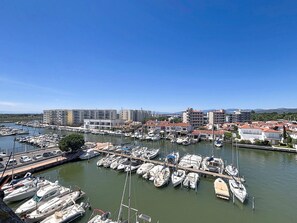 A marina with numerous boats docked, surrounded by residential buildings and a clear sky.