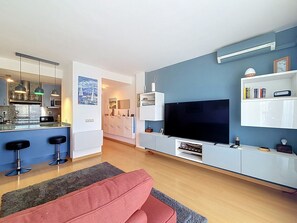 Un salon moderne avec un téléviseur, un canapé et un coin cuisine.