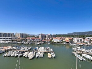 A marina with multiple boats docked, surrounded by buildings with red-tiled roofs. - B.Marina 410 - Atico un dormitorio vista canal (Rosas / Roses)