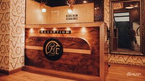 Ein Empfangsschalter mit Holzoptik, ein Logo, eine Dekoration mit einem Hirschkopf und ein Spiegel an der Wand.