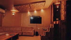 Ein gemütliches Wohnzimmer mit einem flachbildfernseher an einer strukturierten Wand, einem bequemen Sofa, einem Holztisch und einer dekorativen Wandverkleidung.