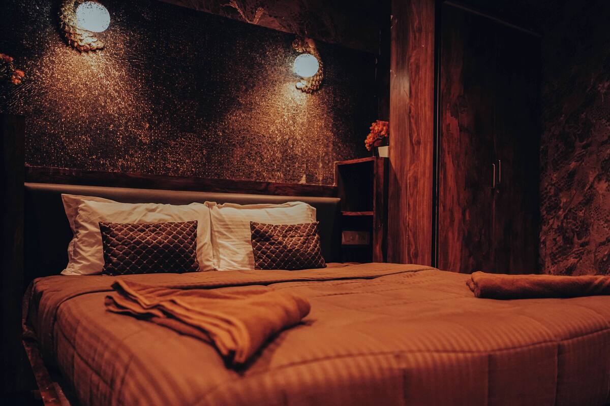 A bedroom with a bed, pillows, a wooden headboard, and a wall with a textured pattern.