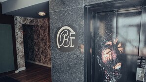 Eine Lobby mit Marmorwand, einem Logo und einer Glastür zum Aufzug.