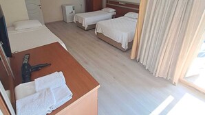 A hotel room with two single beds, a wooden desk with a telephone and towels, a wardrobe, a small refrigerator, and a window with curtains. - YILMAZ OTEL (Akcakoca)