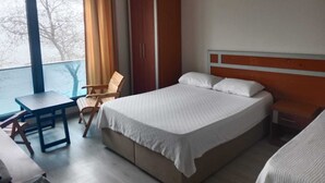 A hotel room with a bed, a desk, a chair, and a wardrobe. - YILMAZ OTEL (Akcakoca)