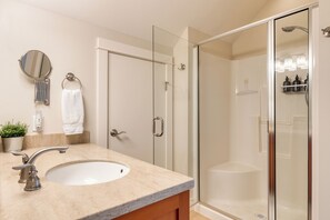 A bathroom with a sink, mirror, towel rack, and a glass-enclosed shower area. - Sunny Backyard, Fireplace, Coastal Access in Peaceful Neighborhood Near Shopping (Langley)