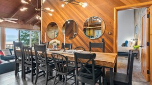 Een houten eetruimte met een grote tafel, stoelen en een hanglamp.
