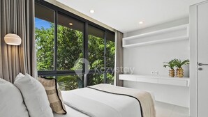 A modern bedroom with a large window, a bed with white linens, a bedside table, and a shelf with decorative items.