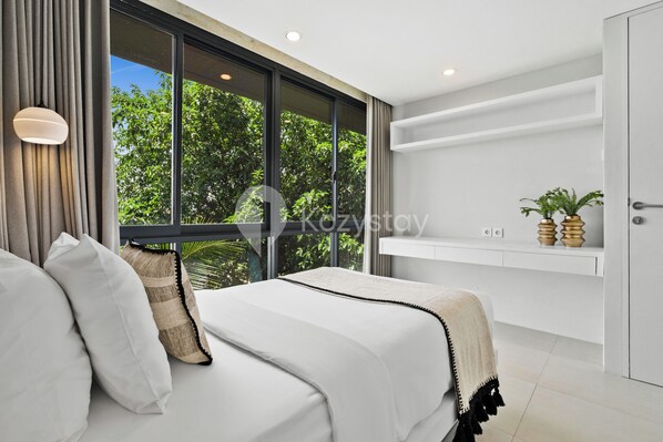 A modern bedroom with a large window, a bed with white linens, a bedside table, and a shelf with decorative items.