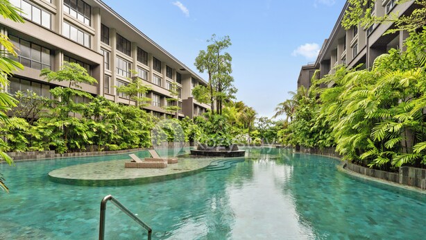 A swimming pool surrounded by lush greenery and modern buildings.