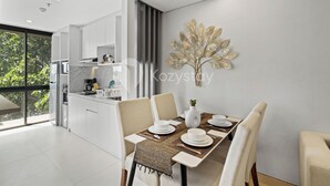 A modern dining area with a table set for four, a vase, and a decorative wall piece.