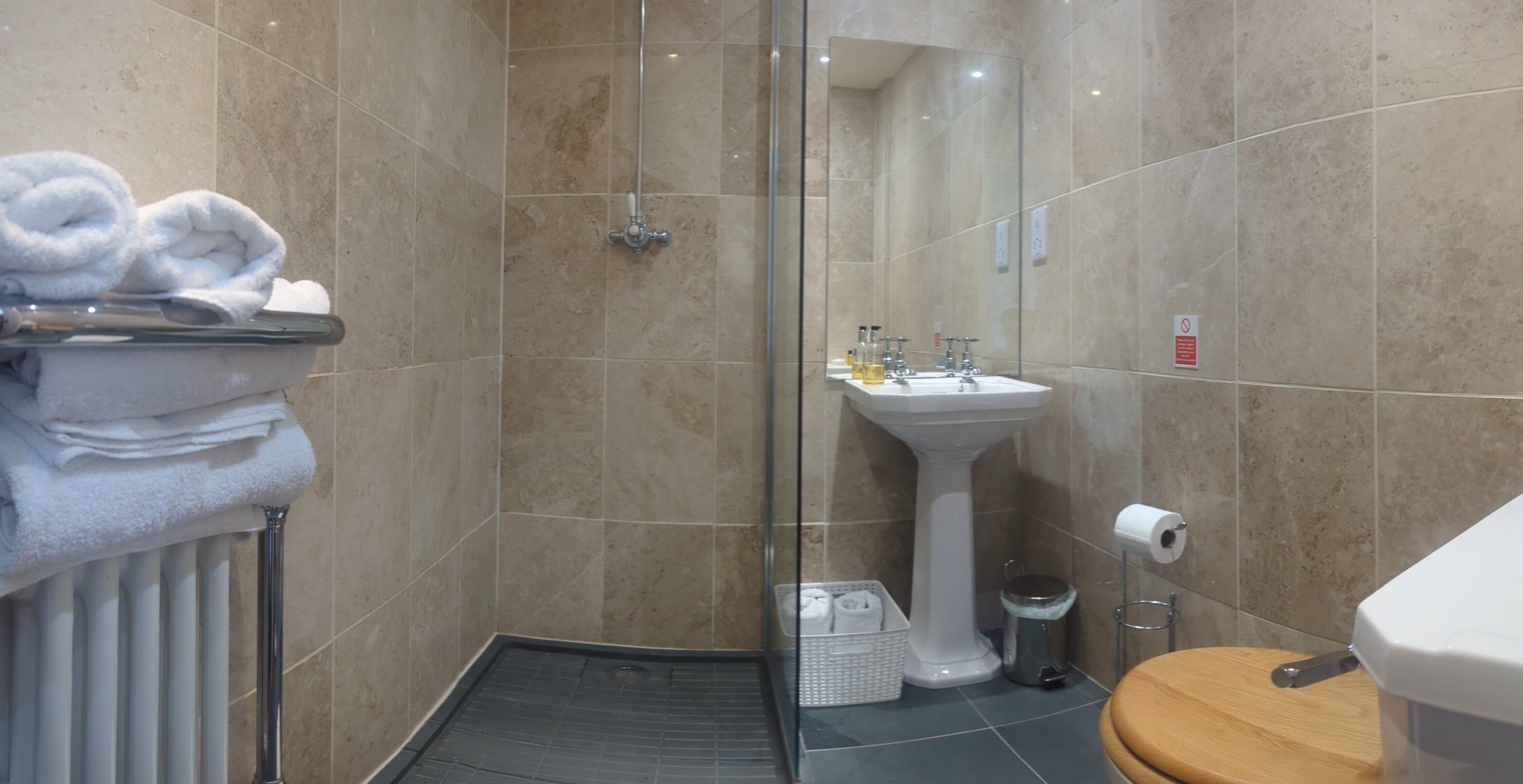 A bathroom with a shower, sink, toilet, and a towel rack with towels.