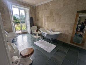 Ein Badezimmer mit Badewanne, Toilette, Waschbecken und einem Sessel.