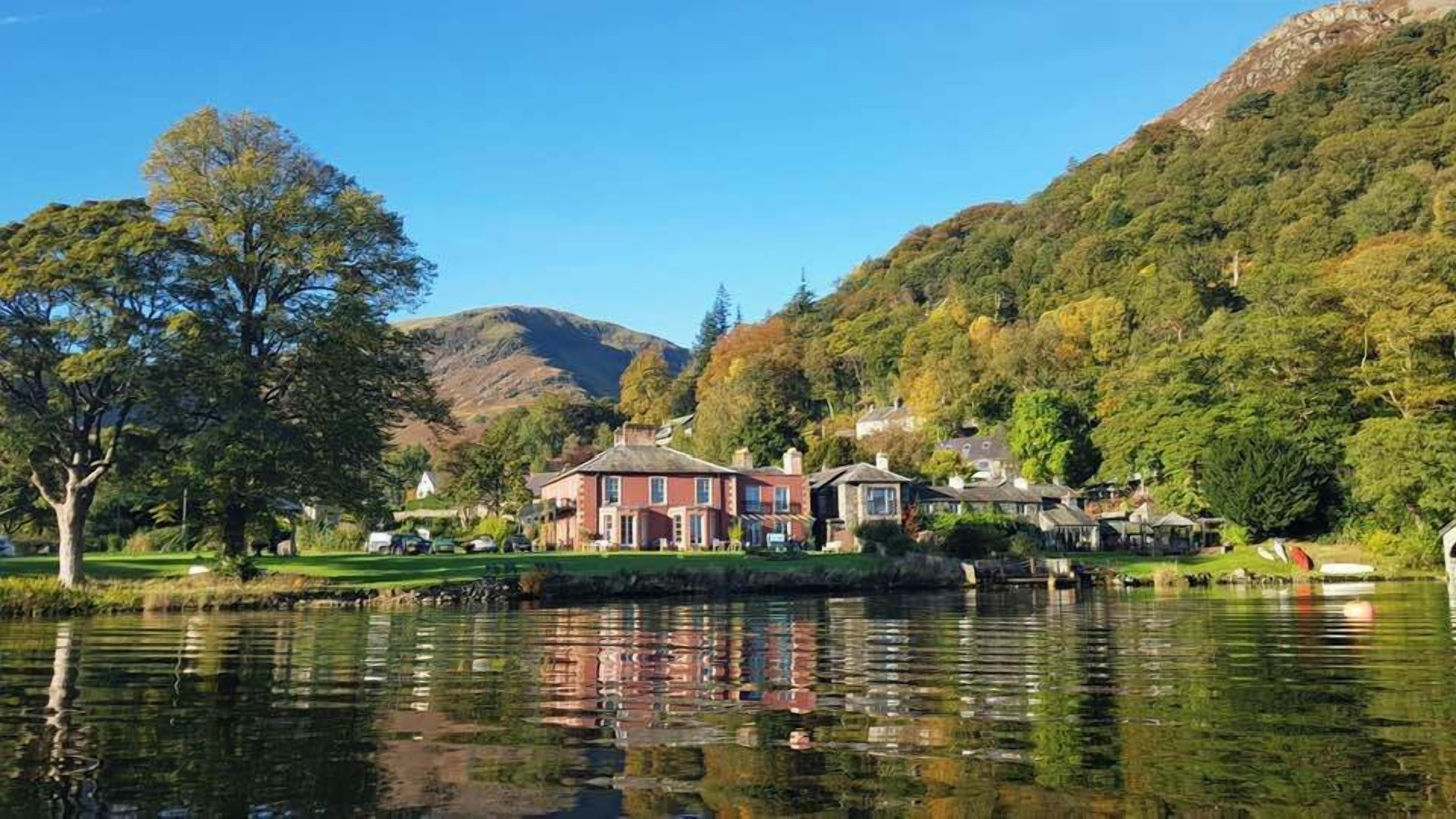 A lakeside property with a large house, smaller buildings, and a mountain backdrop.