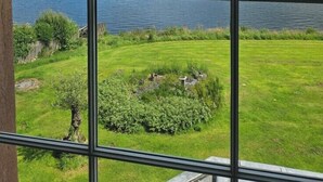 A view through a window of a lake with hills in the background.
