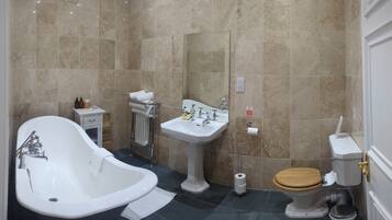 A bathroom with a freestanding bathtub, a pedestal sink, a toilet, and a towel rack.