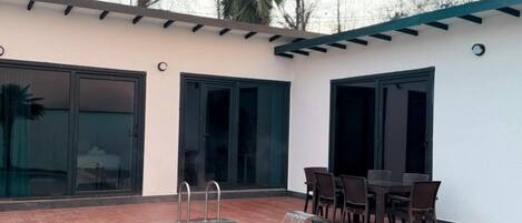 Una piscina con cascada integrada, rodeada de un patio con mobiliario exterior.