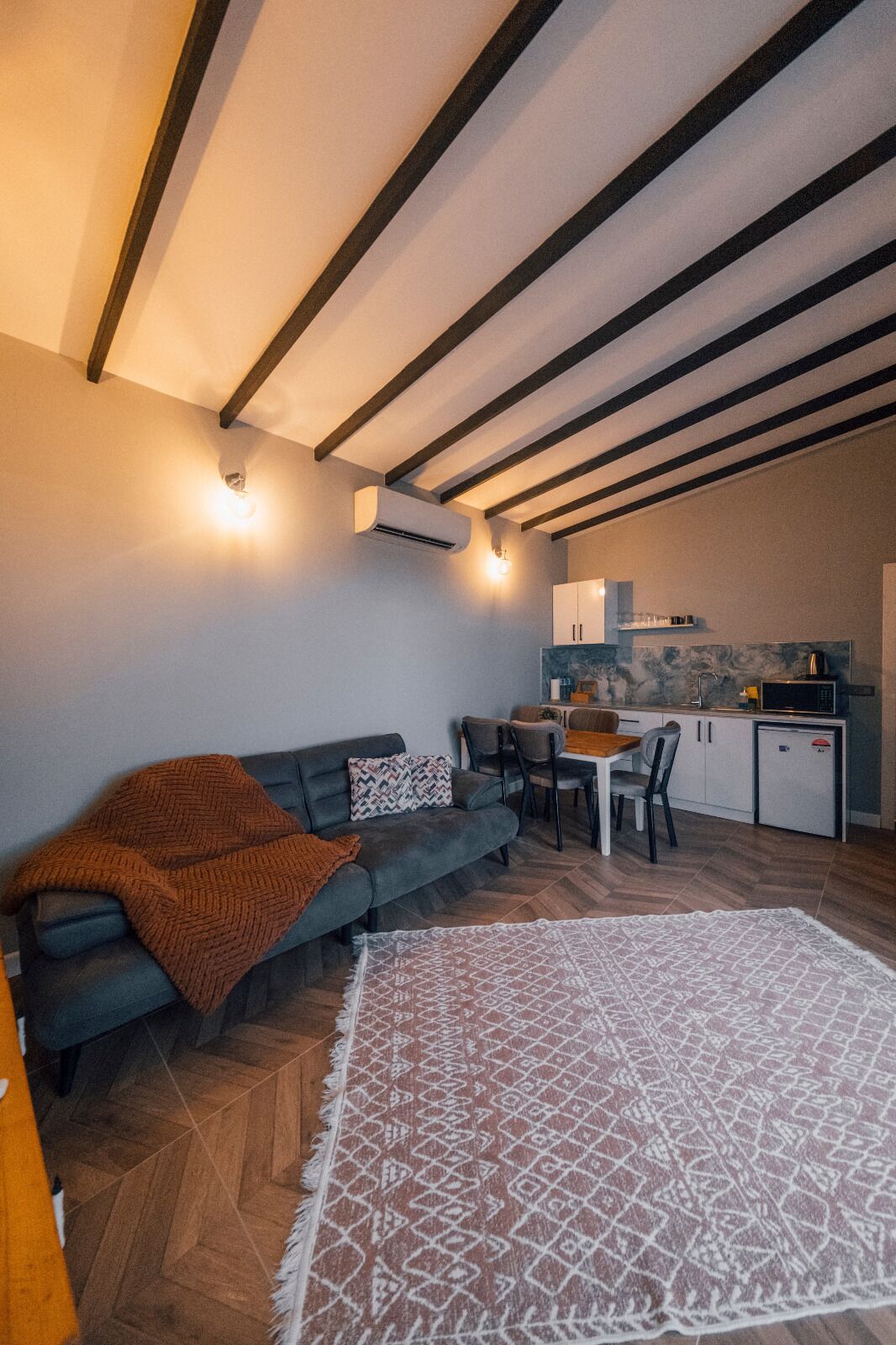 A compact living space with a sofa, a dining table, and a kitchen area.