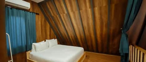 A room with a wooden slatted wall, a bed with white bedding, and blue curtains.