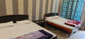 Quarto com duas camas, cabeceira de madeira, papel de parede listrado e cortina estampada.