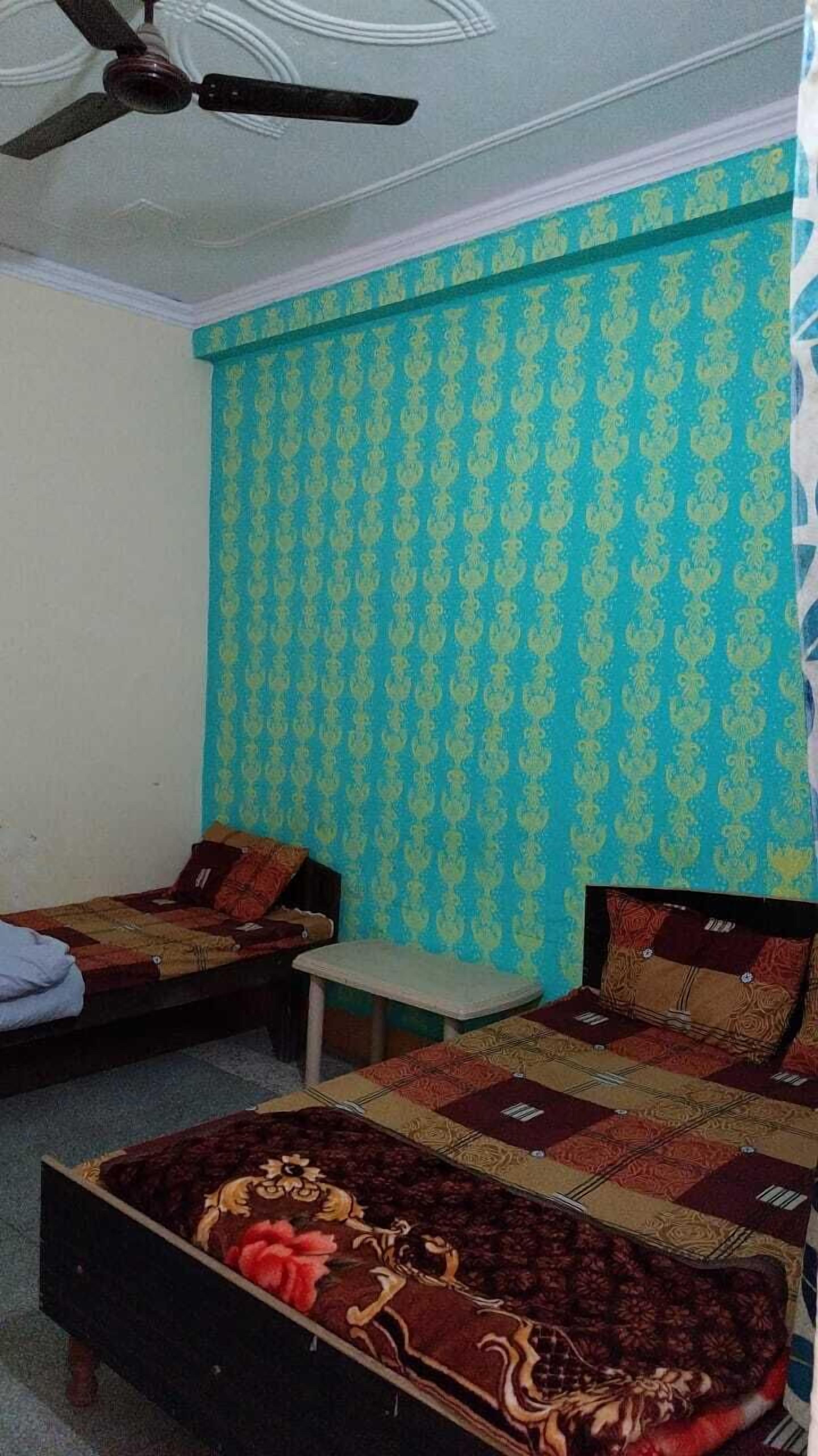 A bedroom with two beds, a small table, and a ceiling fan.