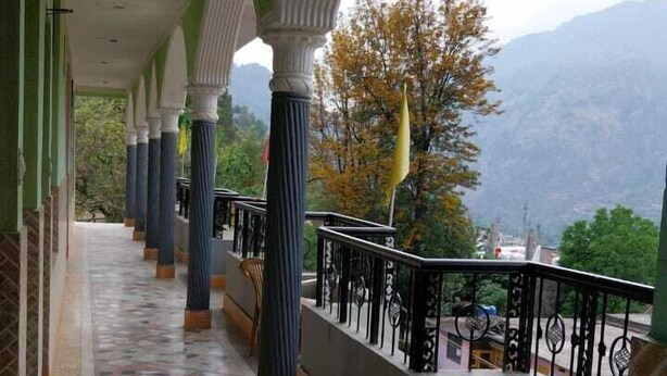 A covered corridor with patterned flooring, columns, and a balcony with a view of mountains. - Hotel Gauri Shankar & Restaurant (Rajgarhi)