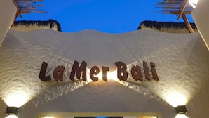 A sign with the text "La Mer Bali" against a textured wall, with a thatched roof structure above. - La Mer Bali Mui Ne (Mui Ne)