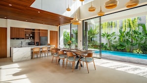 A modern kitchen with a marble island, wooden cabinets, and pendant lighting. - De Dominique Villas Canggu (Canggu)