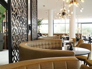 Relax in a stylish space with curved sofas, individual chairs, and a decorative partition.