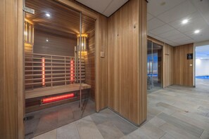 Relax in a serene sauna area with a glass door and comfortable bench.