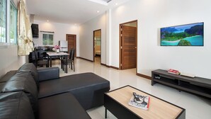 Una sala de estar moderna con un sofá negro, una mesa de centro de madera y un televisor de pantalla plana montado en la pared.
