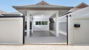 Un espacio exterior techado con techo, una puerta y un buzón.