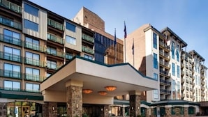 A multi-story hotel with a central entrance, balconies, and a flag.