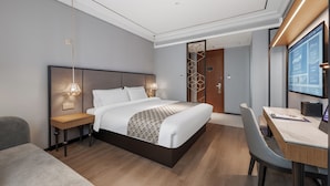 Une chambre d’hôtel moderne, dotée d’un grand lit, de tables de chevet, d’un bureau et d’une chaise.