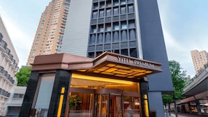 L’entrée d’un hôtel moderne, avec une enseigne bien visible, une façade en verre et un environnement urbain environnant.