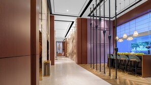 Un hall d’hôtel moderne avec un sol en marbre, un comptoir d’accueil et un espace bar doté de tabourets.