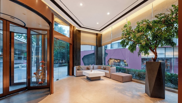 Un hall d’entrée moderne avec un espace salon, de grandes fenêtres et un arbre.