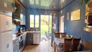 Een compacte keuken met een eethoek, uitzicht op de omgeving en een plafond met strakke lijnen.