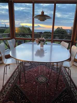 A round table with white chairs, a vase with flowers, and a hanging light fixture.