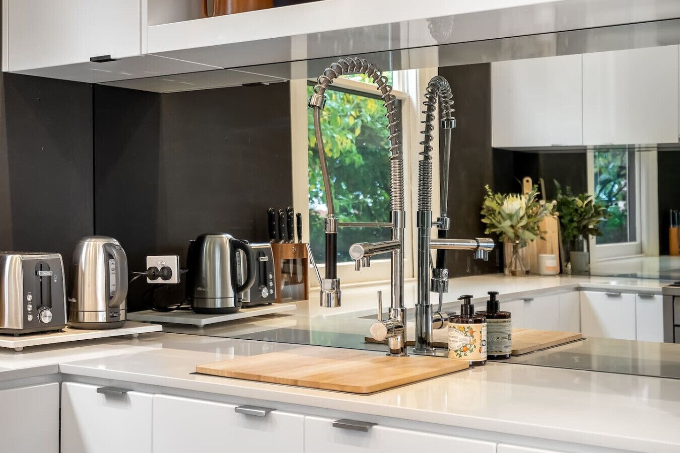 A modern kitchen with a stainless steel faucet, a kettle, a toaster, and a coffee maker on the counter.