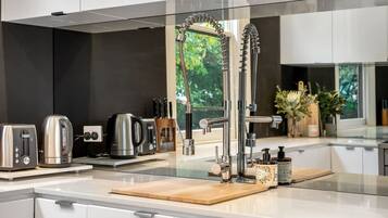 A modern kitchen with a stainless steel faucet, a kettle, a toaster, and a coffee maker on the counter.