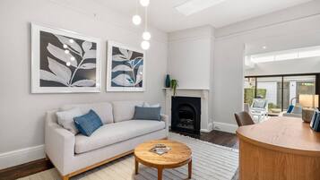 A living room with a sofa, coffee table, fireplace, and artwork on the wall.
