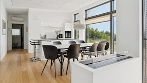 Une cuisine moderne avec un coin repas, de grandes fenêtres et une vue sur la verdure.