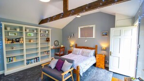 Een knus slaapkamer met een bed, een houten bankje, een boekenkast en een bureau.