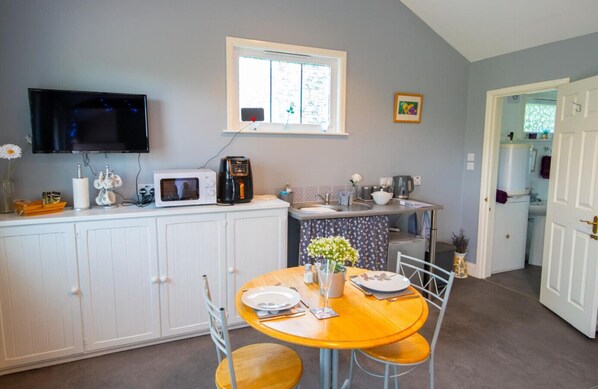 A compact kitchen with white cabinets, a microwave, a coffee maker, and a window above the sink.