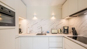 A modern kitchen with a built-in oven, a sink, a toaster, and a coffee maker. - Lornsen-Hof, App. 2 - Modern apartment on the ground floor with 2 rooms on approx. 50 m², (Sylt)