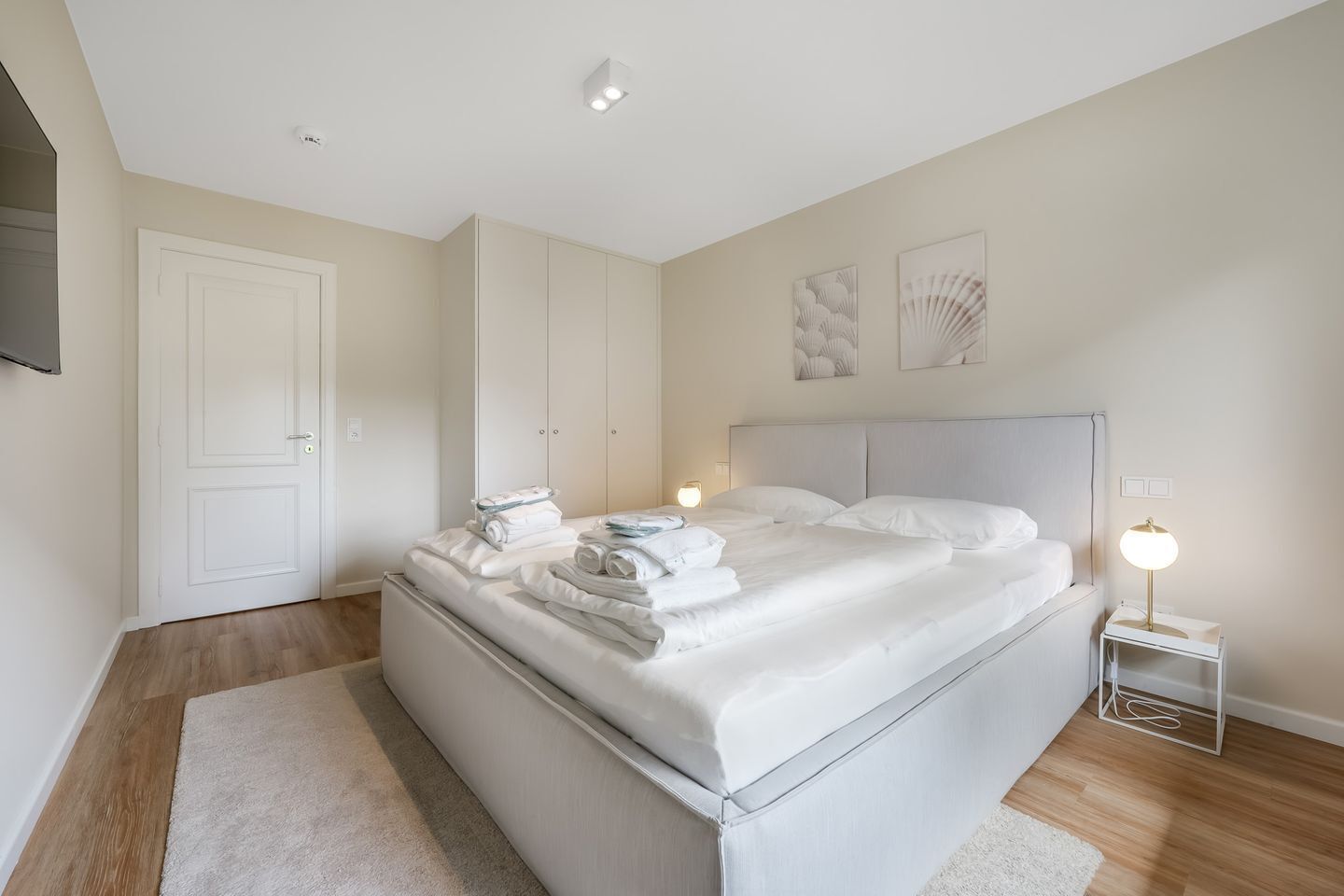 Een hotelkamer met een groot bed, een nachtkastje met een lamp en een kledingkast.