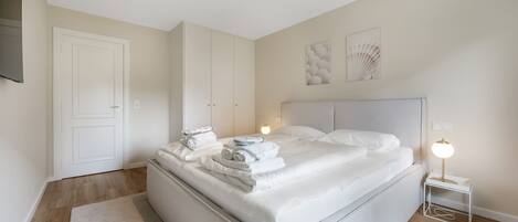 Een hotelkamer met een groot bed, een nachtkastje met een lamp en een kledingkast.