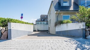 A modern building with a paved entrance, a parking sign, and a concrete barrier. - Lornsen-Hof, App. 2 - Modern apartment on the ground floor with 2 rooms on approx. 50 m², (Sylt)