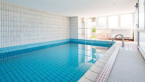 Une piscine aux murs recouverts de carreaux et dont l’eau est d’un bleu limpide.